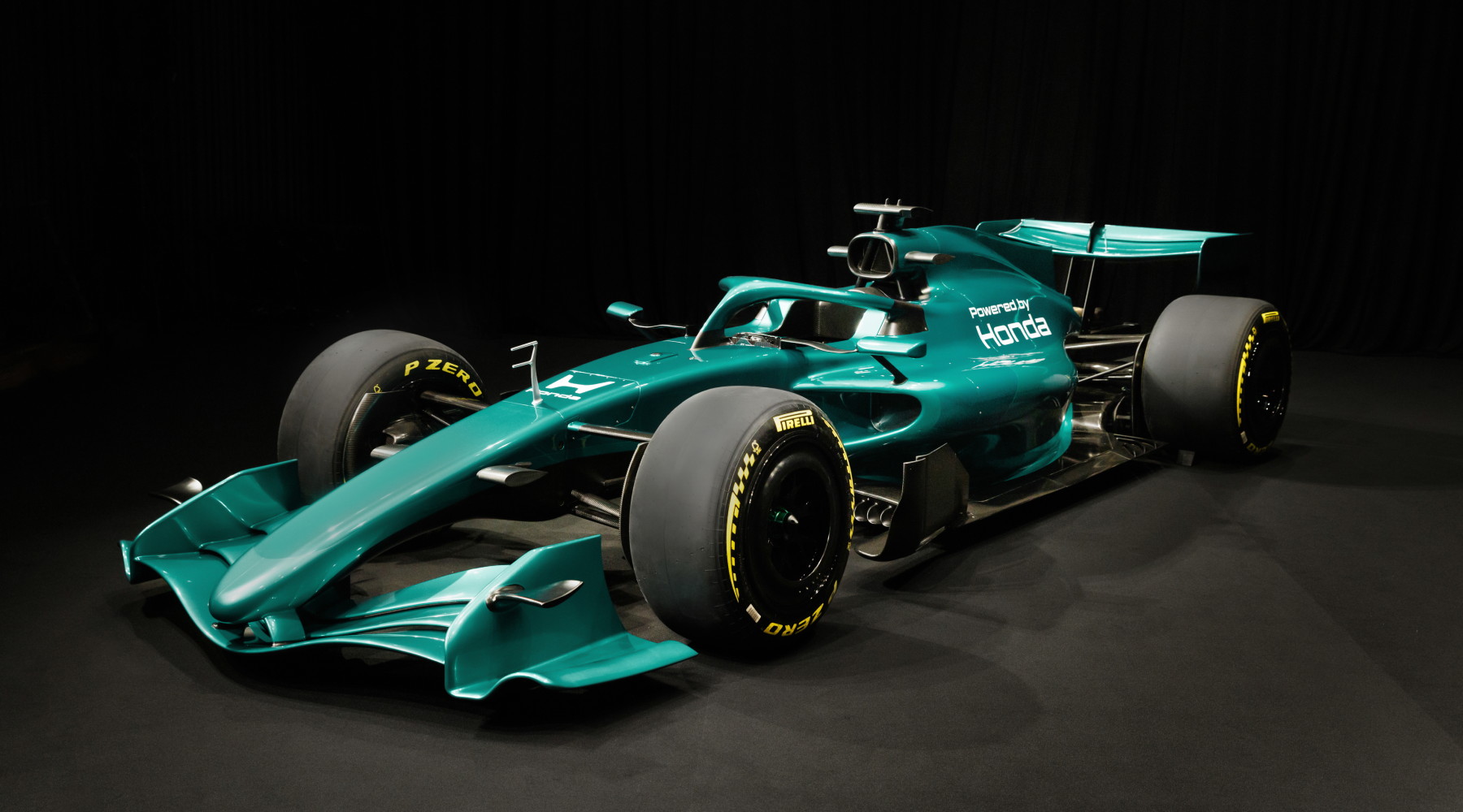 A turquoise Formula 1 race car with Honda branding, featuring aerodynamic bodywork, large Pirelli tires, and a prominent rear wing, positioned against a black background.